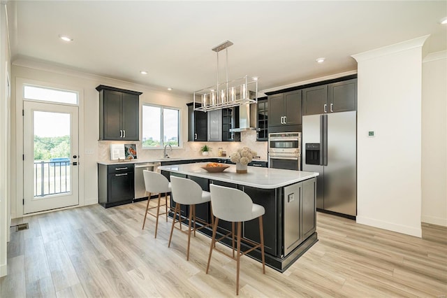 kitchen with appliances with stainless steel finishes, decorative light fixtures, crown molding, a center island, and a kitchen bar