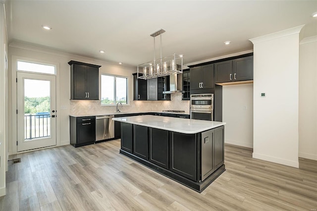 kitchen with stainless steel appliances, a kitchen island, pendant lighting, ornamental molding, and sink