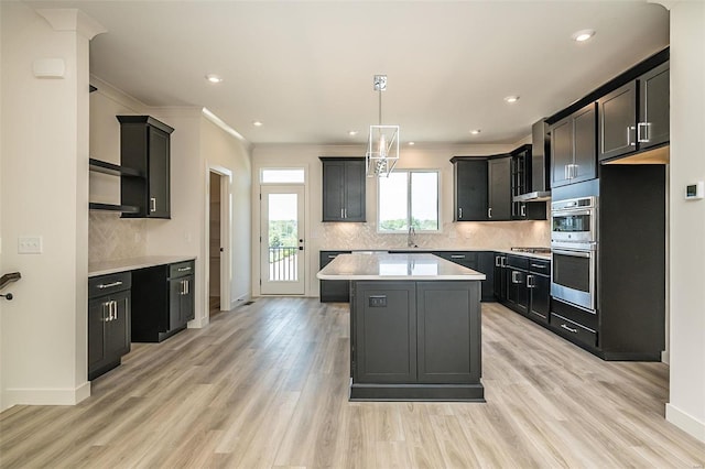 kitchen with light wood-type flooring, decorative light fixtures, a kitchen island, backsplash, and ornamental molding