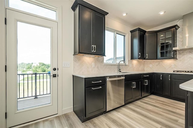 kitchen with a wealth of natural light, light hardwood / wood-style floors, sink, dishwasher, and wall chimney exhaust hood