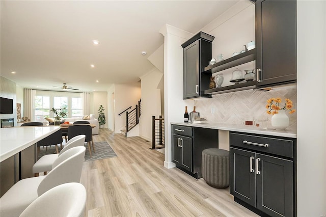 kitchen featuring light wood-type flooring, ceiling fan, and backsplash