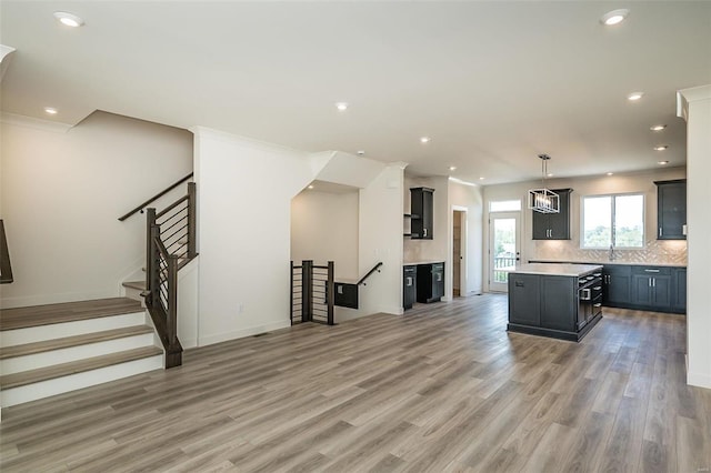 kitchen featuring hardwood / wood-style flooring, a kitchen island, sink, backsplash, and pendant lighting