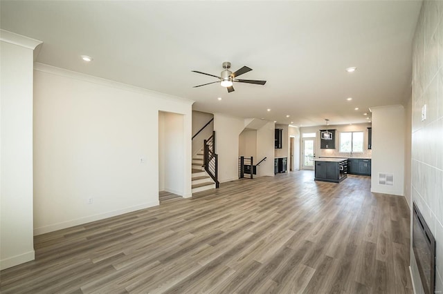 unfurnished living room with ornamental molding, hardwood / wood-style flooring, and ceiling fan