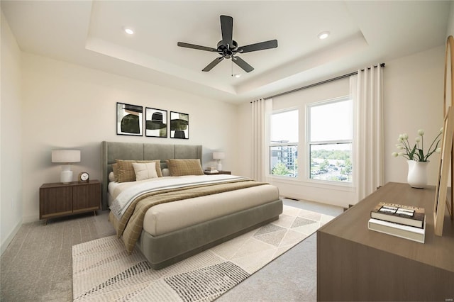 bedroom featuring ceiling fan, a raised ceiling, and light colored carpet