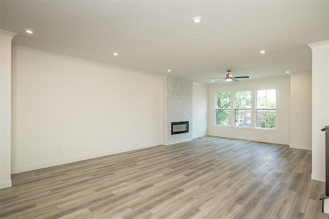 unfurnished living room with ceiling fan, ornamental molding, light hardwood / wood-style floors, and a high end fireplace