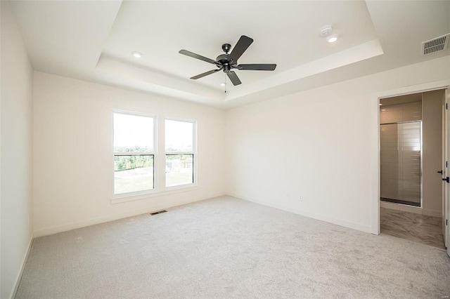 carpeted spare room featuring ceiling fan and a tray ceiling