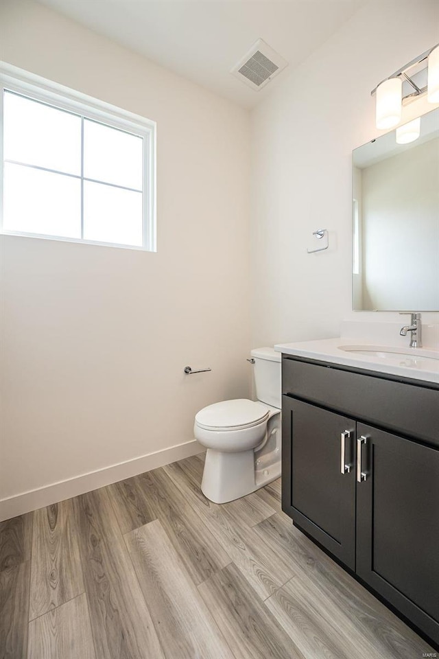 bathroom featuring toilet, hardwood / wood-style flooring, and vanity