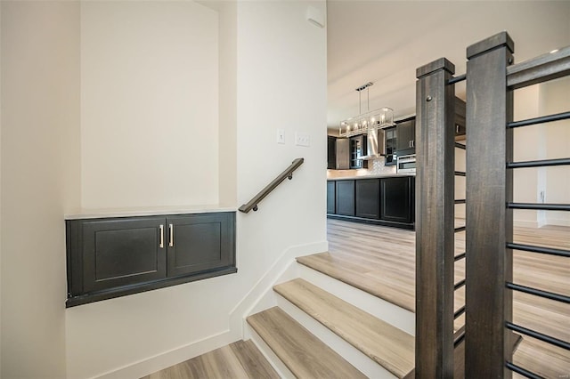 staircase featuring hardwood / wood-style flooring and a chandelier