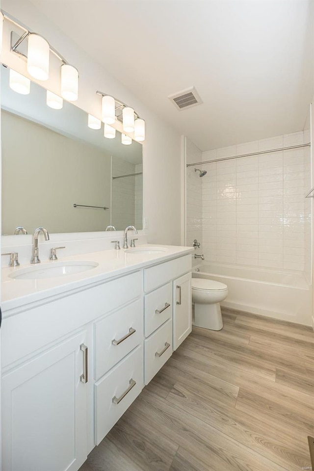 full bathroom featuring tiled shower / bath combo, hardwood / wood-style flooring, vanity, and toilet