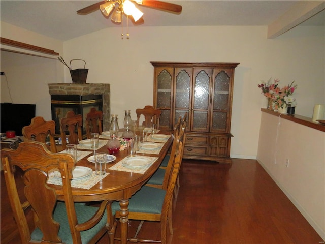 dining room featuring ceiling fan, a fireplace, dark hardwood / wood-style floors, and lofted ceiling with beams