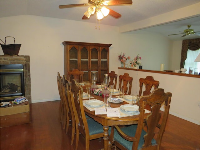 dining room with dark wood-type flooring, ceiling fan, lofted ceiling with beams, and a fireplace