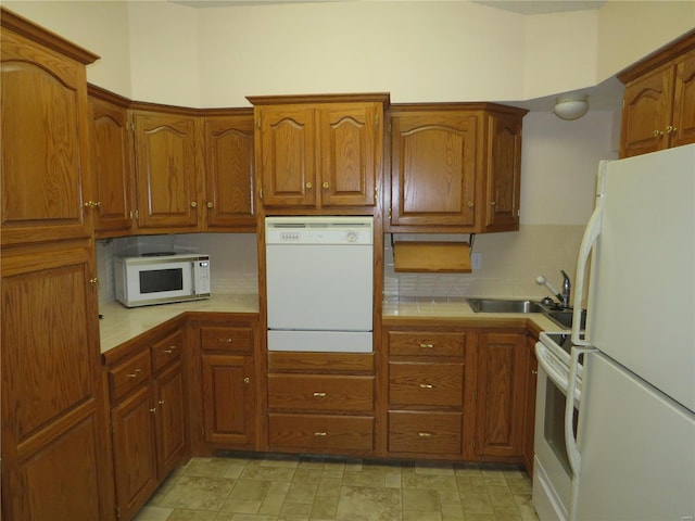 kitchen with white appliances, backsplash, sink, and tile counters