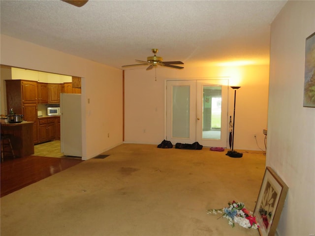 interior space featuring ceiling fan, light colored carpet, and a textured ceiling