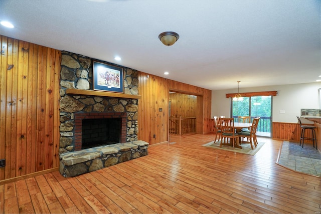 living area with a stone fireplace, recessed lighting, hardwood / wood-style floors, and wooden walls