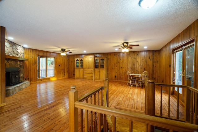 living area featuring a stone fireplace, a ceiling fan, and light wood-style floors