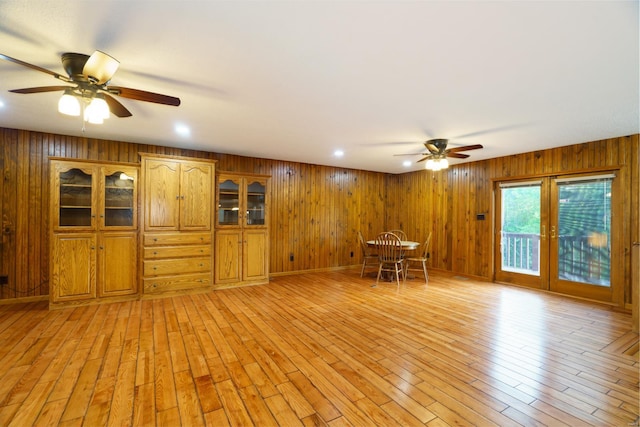 unfurnished living room featuring ceiling fan, recessed lighting, light wood-type flooring, and wooden walls