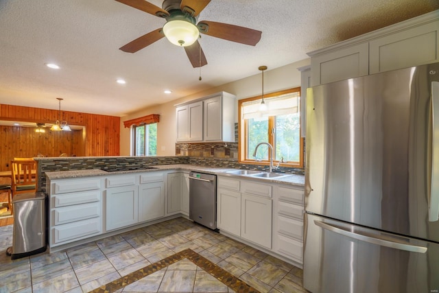 kitchen featuring wooden walls, a peninsula, a sink, stainless steel appliances, and backsplash