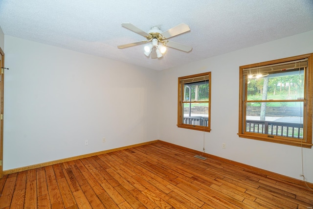 unfurnished room with a ceiling fan, visible vents, light wood-style flooring, and a textured ceiling