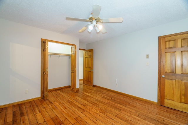 unfurnished bedroom featuring a closet, baseboards, a textured ceiling, and light wood finished floors