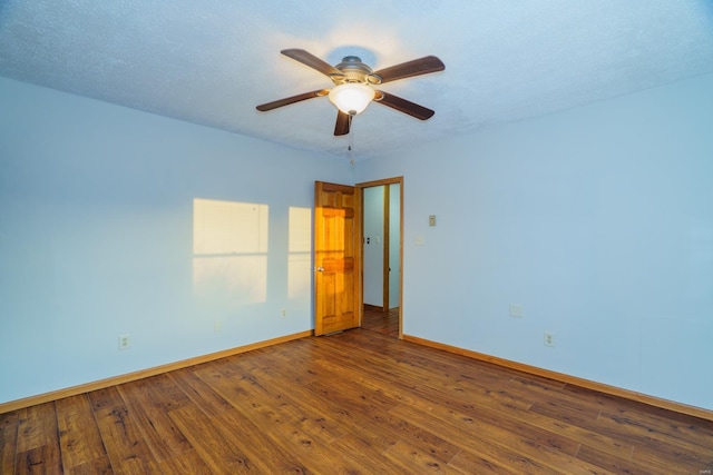 empty room with dark wood-style floors, ceiling fan, baseboards, and a textured ceiling