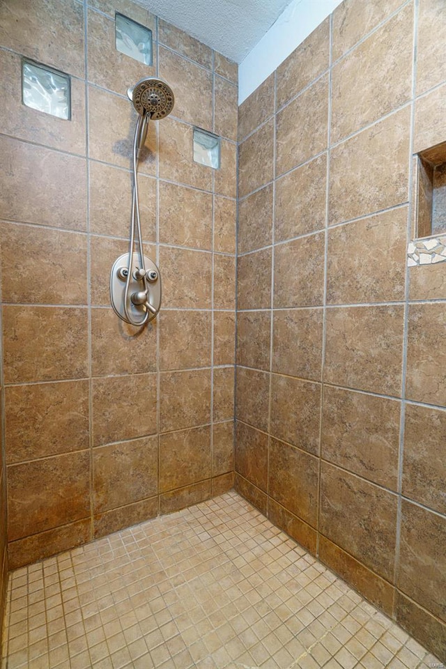 bathroom featuring a tile shower and a textured ceiling