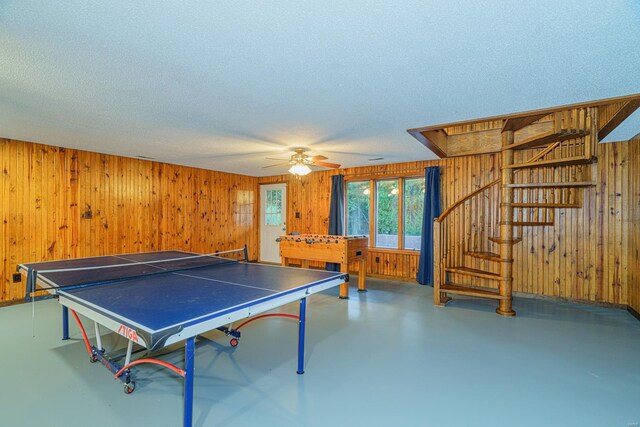 playroom with wood walls, concrete floors, and a textured ceiling