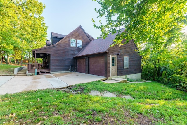 rear view of property featuring a garage, a yard, and concrete driveway