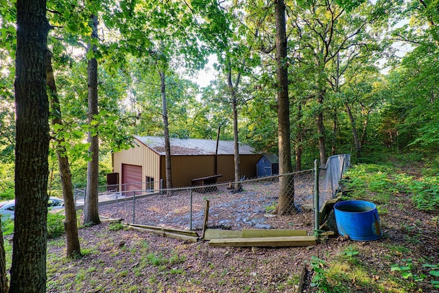 back of house with a garage, an outbuilding, and fence