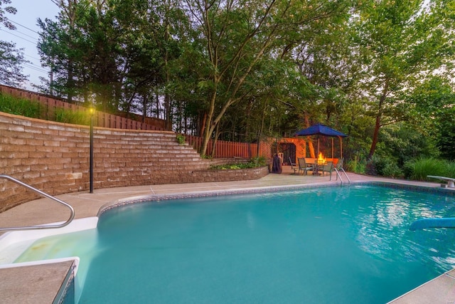 pool with fence, a diving board, and a patio