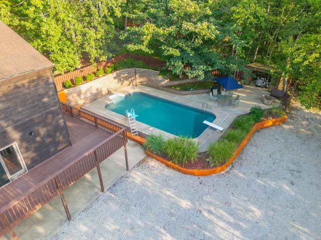 view of swimming pool with a diving board, a patio area, a fenced backyard, and a fenced in pool