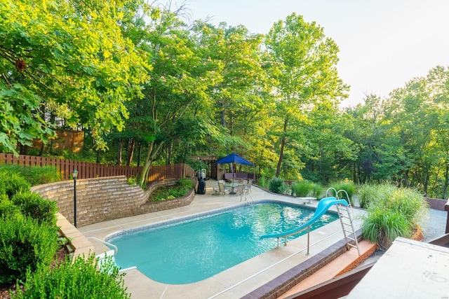 view of swimming pool featuring a patio, a water slide, fence, and a fenced in pool