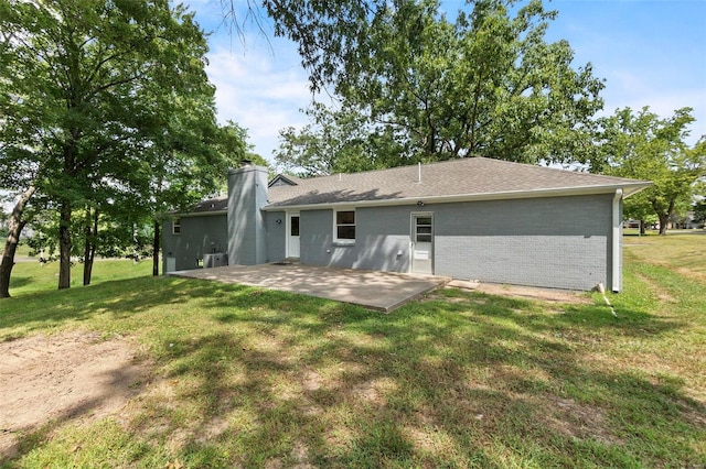 back of house with brick siding, a patio, a chimney, and a lawn