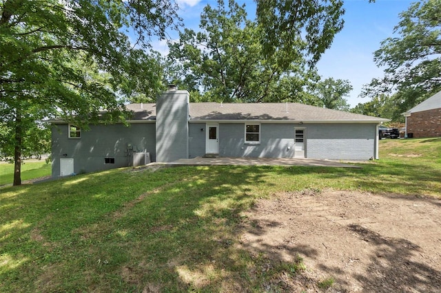 rear view of house with central AC, a yard, a chimney, and a patio