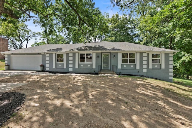 single story home featuring a garage, concrete driveway, and brick siding