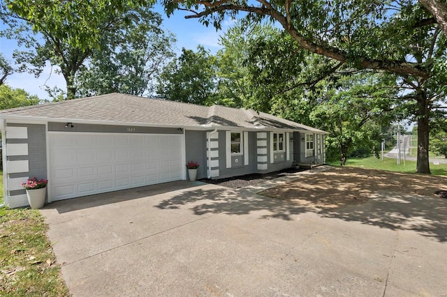 view of front facade with driveway, an attached garage, roof with shingles, and brick siding