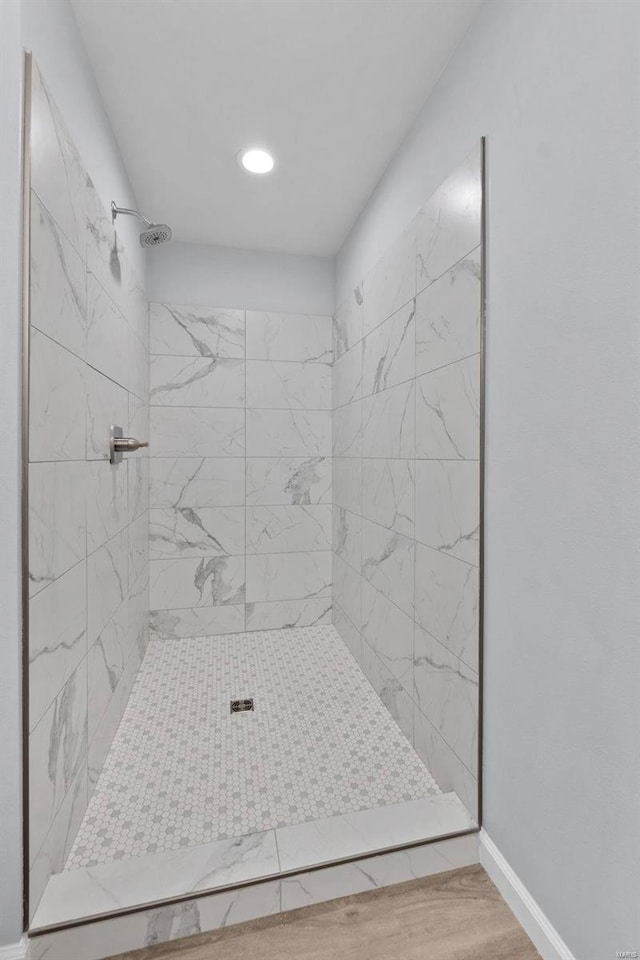 full bathroom with baseboards, tiled shower, and wood finished floors