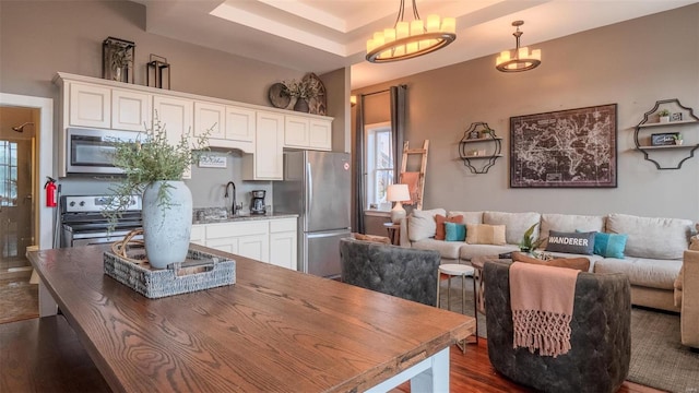 dining room featuring sink, dark hardwood / wood-style floors, a raised ceiling, and a notable chandelier