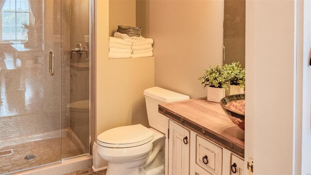 bathroom featuring a shower with shower door, vanity, and toilet