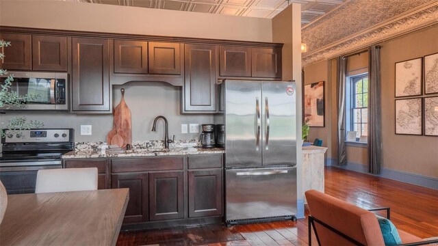 kitchen featuring stainless steel appliances, sink, dark brown cabinetry, dark hardwood / wood-style floors, and ornamental molding