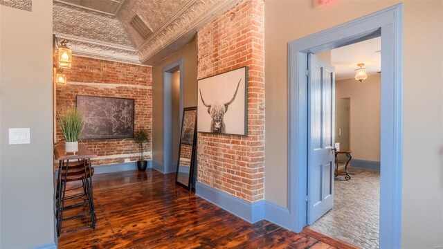 corridor with brick wall and hardwood / wood-style floors