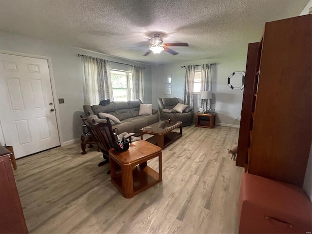 living room with light wood-type flooring, ceiling fan, and a textured ceiling