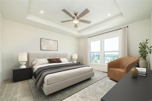 carpeted bedroom with ceiling fan and a tray ceiling