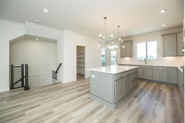 kitchen with gray cabinetry, light hardwood / wood-style floors, decorative light fixtures, decorative backsplash, and a kitchen island