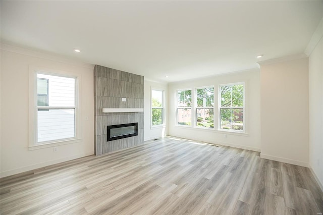 unfurnished living room featuring a tile fireplace, light hardwood / wood-style floors, and ornamental molding