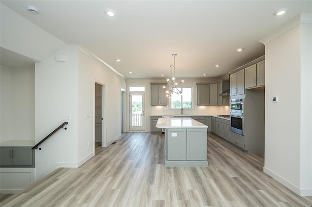 kitchen featuring gray cabinetry, light hardwood / wood-style flooring, a kitchen island, and pendant lighting