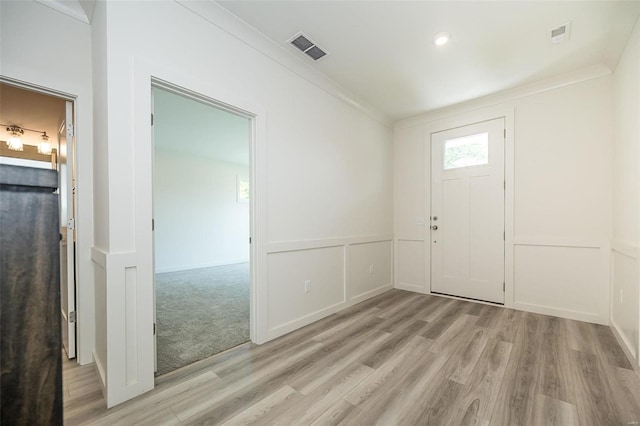 foyer entrance featuring crown molding and light wood-type flooring