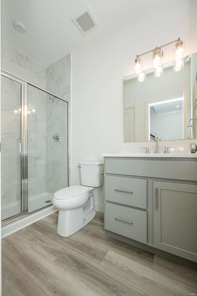 bathroom featuring vanity, wood-type flooring, an enclosed shower, and toilet