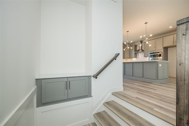 staircase featuring wood-type flooring and a notable chandelier