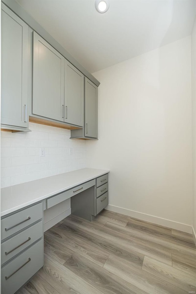 unfurnished office featuring built in desk and light wood-type flooring