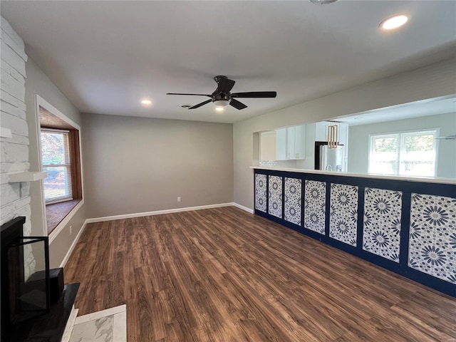 unfurnished room featuring ceiling fan, dark hardwood / wood-style floors, and a fireplace